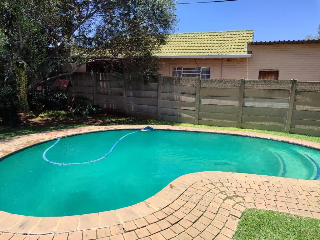 een klein zwembad in een tuin met een hek bij Mvuli haven in Pretoria