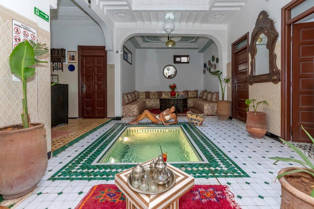 een vrouw op een bank naast een zwembad bij Riad HAFSSA & Spa in Marrakesh