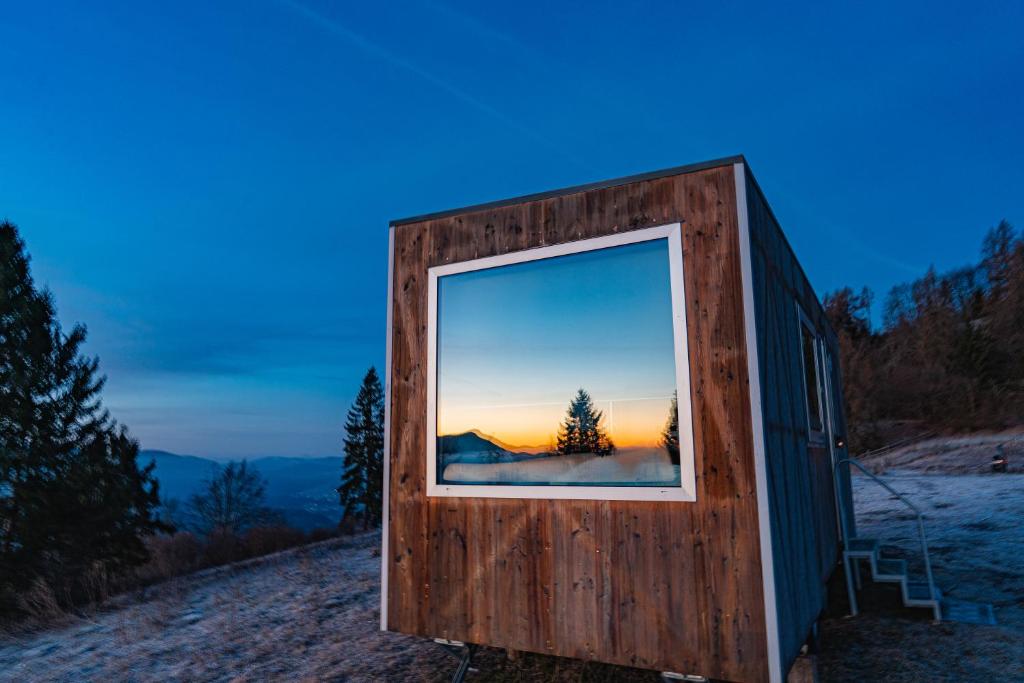 a building with a window on a hill with the sunset at Rallentare immersi nel verde di Cima Lan 