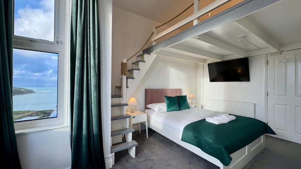 a bedroom with a bed and a staircase and a window at Reef Lodge in Newquay