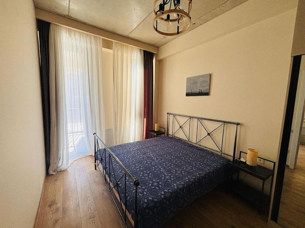 Un dormitorio con una cama y una ventana grande. en Stylish, Brand-New 2BR Apt with Panoramic View, en Itʼkhvisi