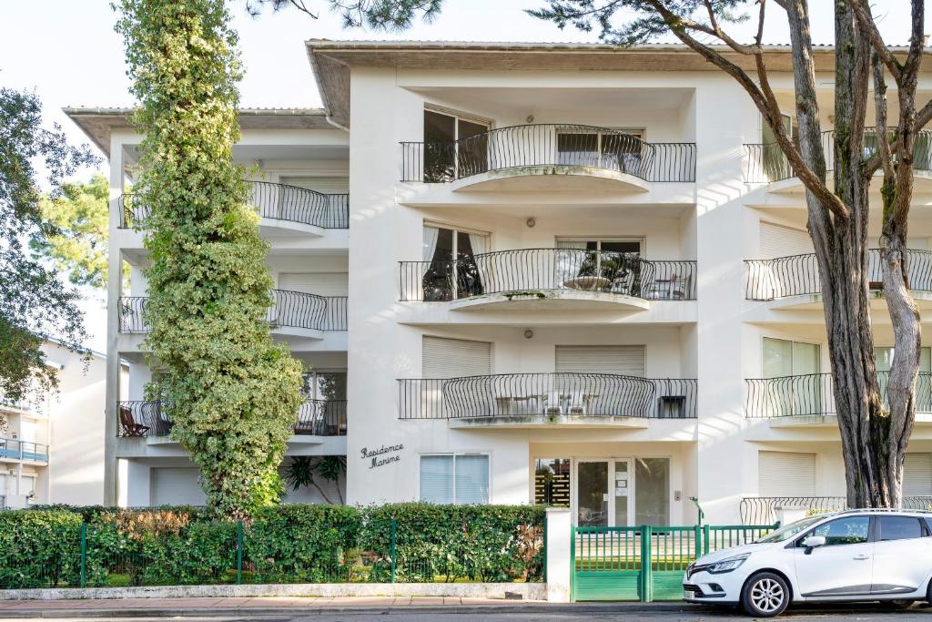 a white building with balconies and a car parked in front at Spacieux T3 cosy au cœur d’Hossegor in Soorts-Hossegor