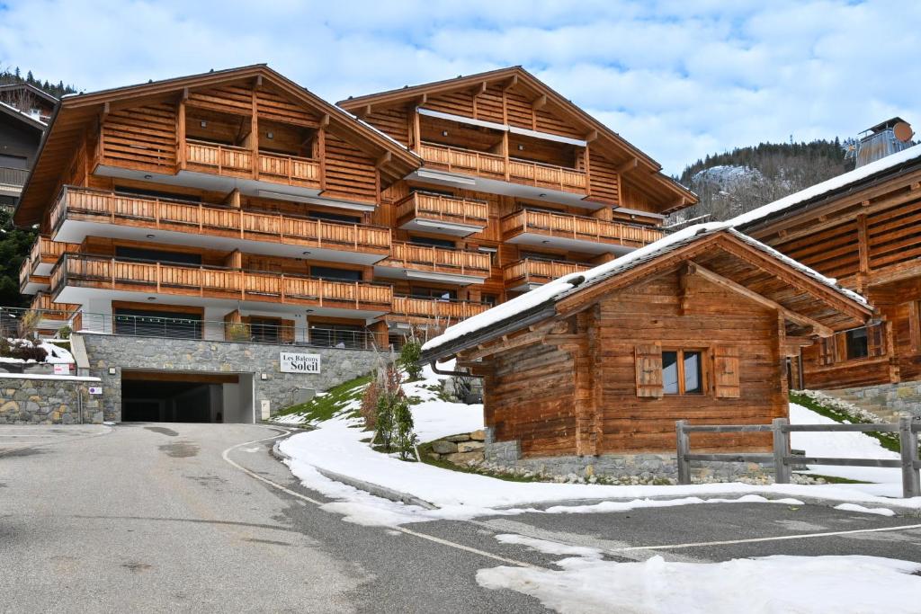 a large wooden building with snow on the ground at Appartement Le Barat'ski in Le Grand-Bornand