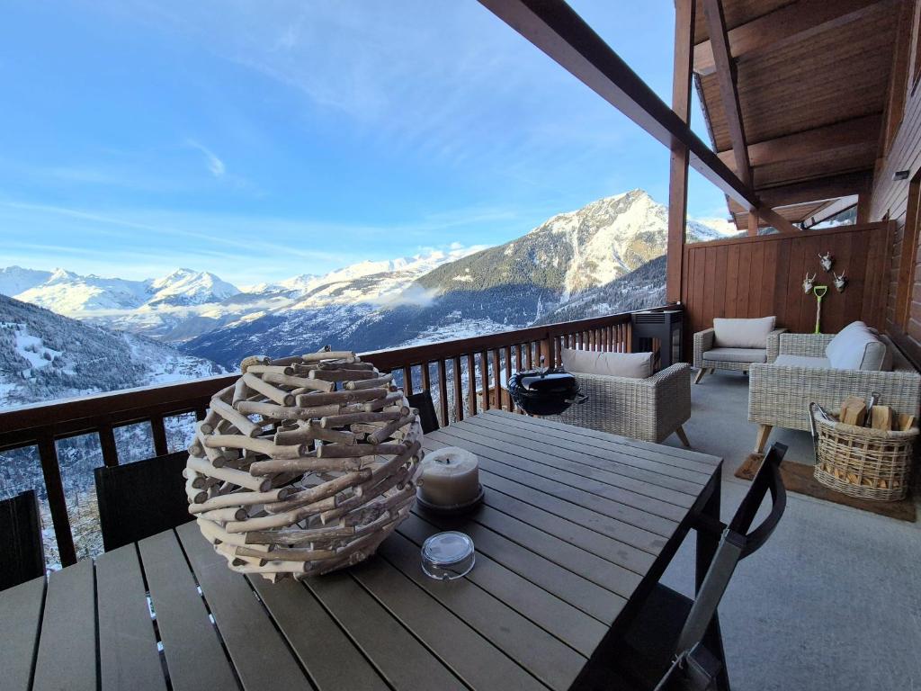 a wooden table on a balcony with a view of mountains at Élégant Duplex - Sainte Foy Station - 10 pers in Sainte-Foy-Tarentaise