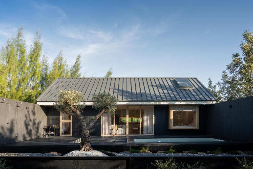 a house with a black roof and a tree at Kuro Pool Villa Khaoyai in Ban Wang Sai