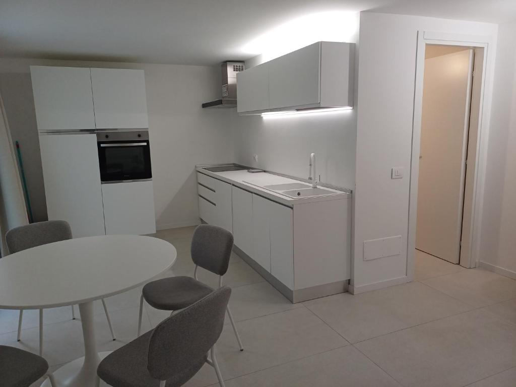 een witte keuken met een tafel en een tafel en stoelen bij Casa Vacanze Derby Appartamenti in Misano Adriatico