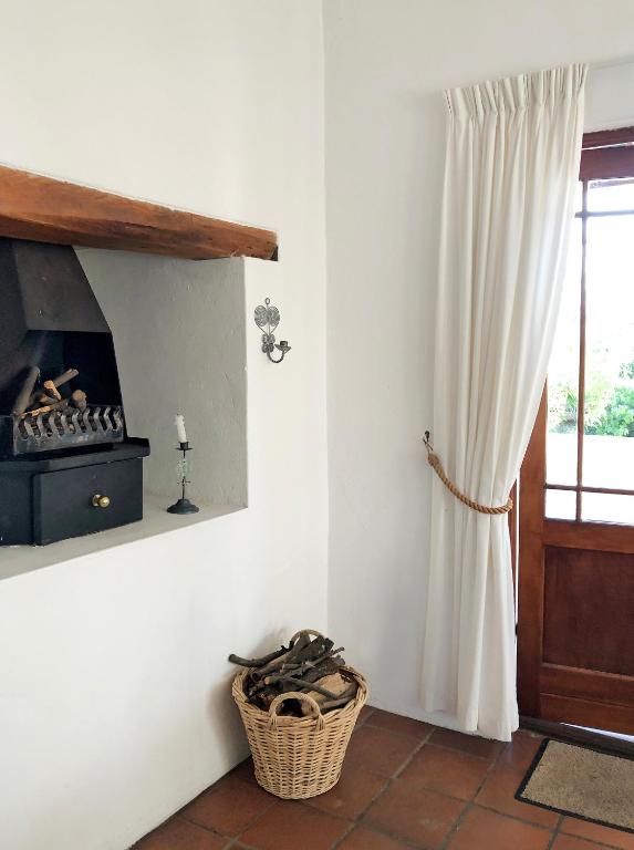 a living room with a fireplace and a window at Eensgevonden Vineyard Cottages in Rawsonville