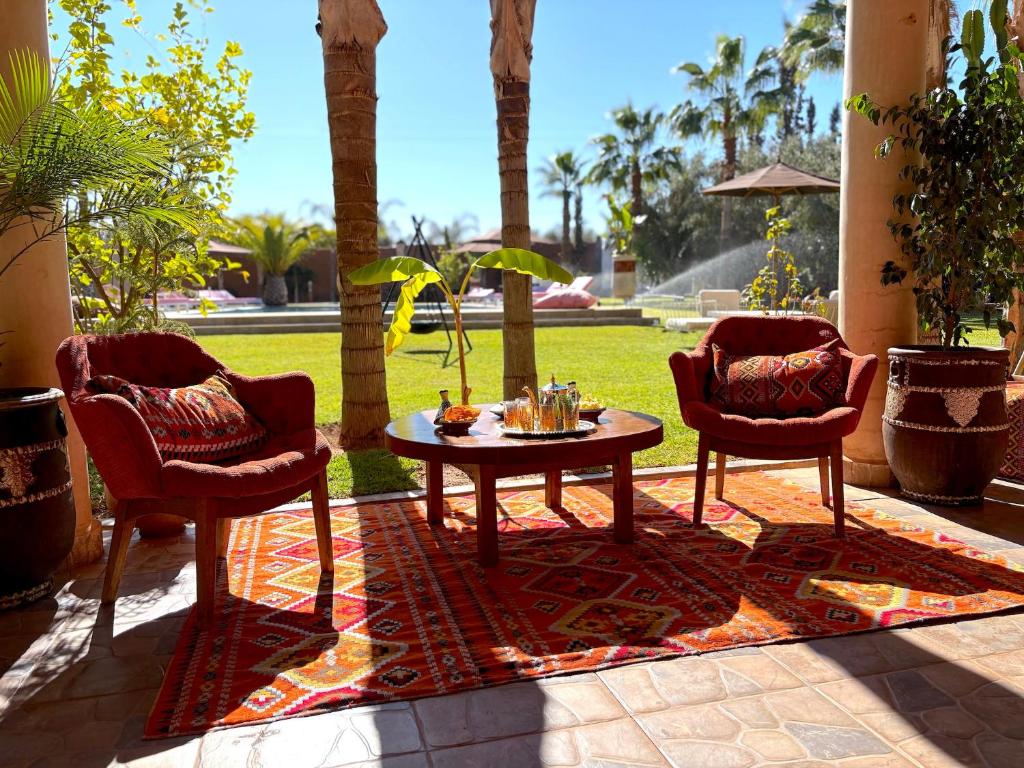 a patio with two chairs and a table on a rug at Palais Bohemia in El Rhechat