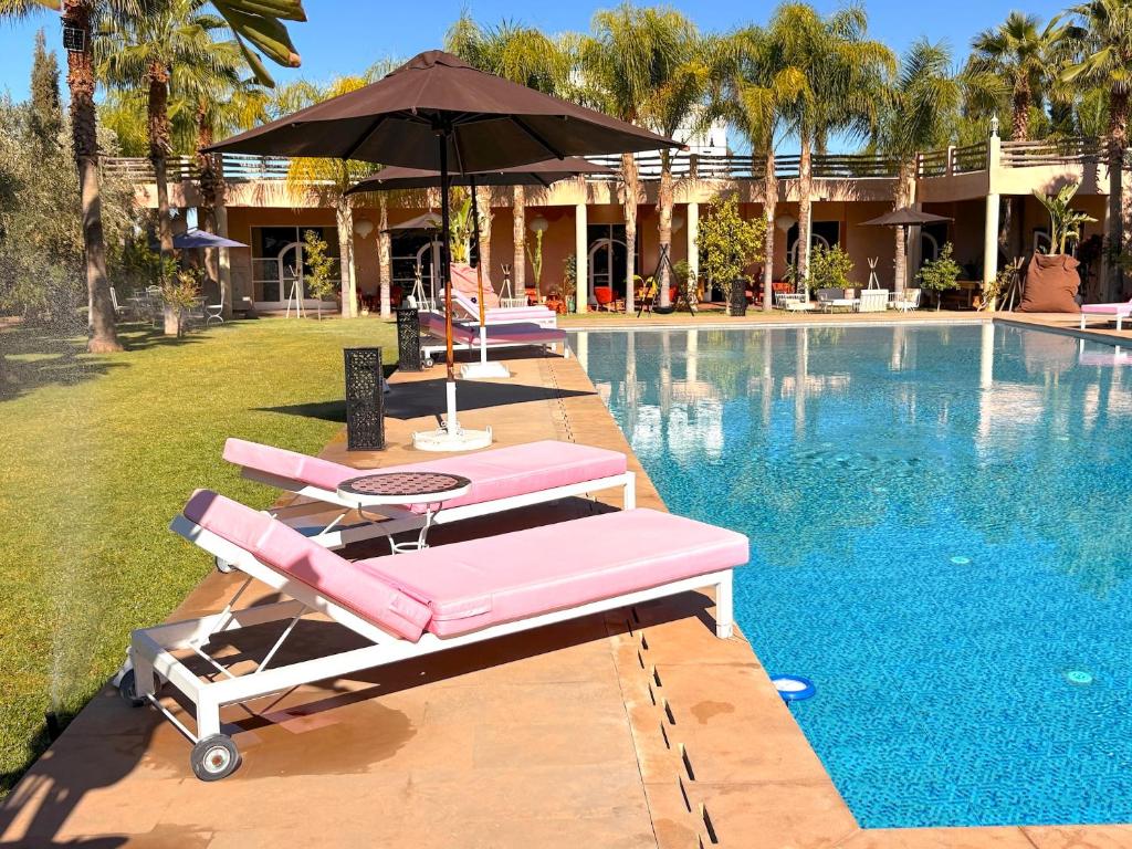 eine Reihe von rosa Liegestühlen neben einem Pool in der Unterkunft Palais Bohemia in El Rhechat