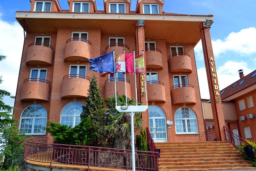 a large red brick building with flags in front of it at Hotel Avenida III in Villadangos del Páramo