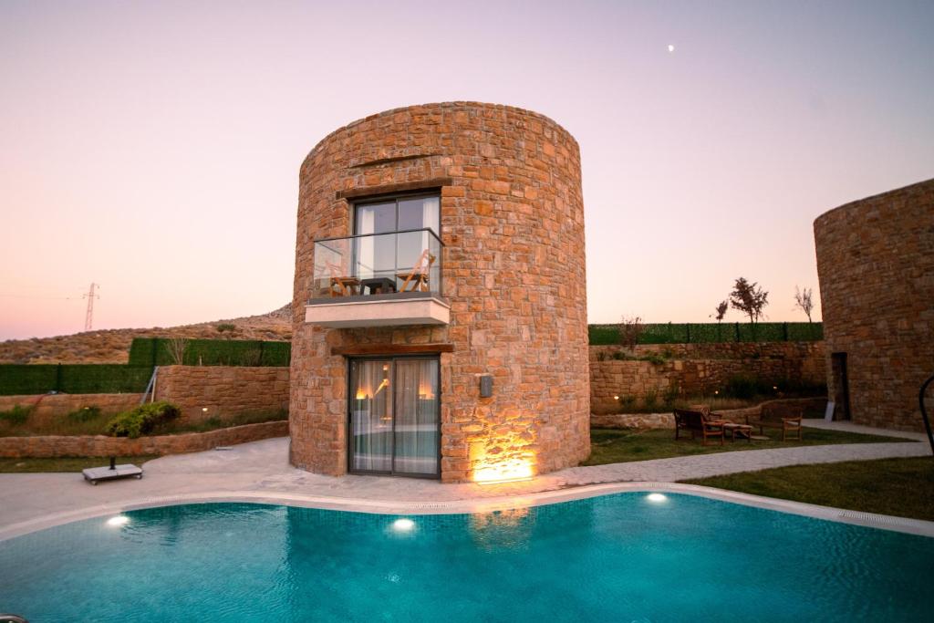 a house with a swimming pool in front of a building at Blue Inn Hotel in Gökçeada