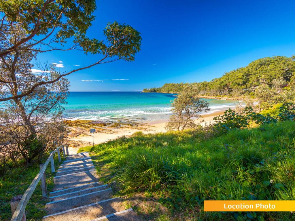 una escalera que conduce a una playa con el océano en Seascape Macleay Street - walk to beach, en Narrawallee