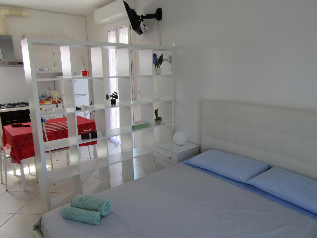 een witte slaapkamer met een bed en een keuken bij Appartamento l'Ulivo in Gradara