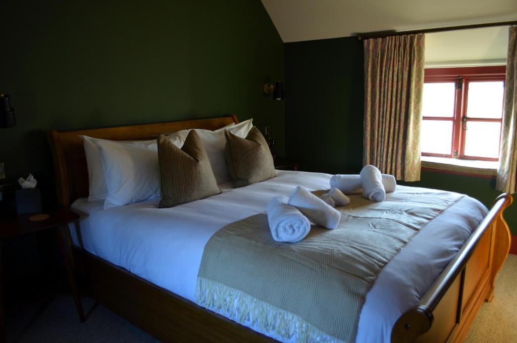 um quarto com uma cama grande com toalhas em The Hollow Bottom em Guiting Power