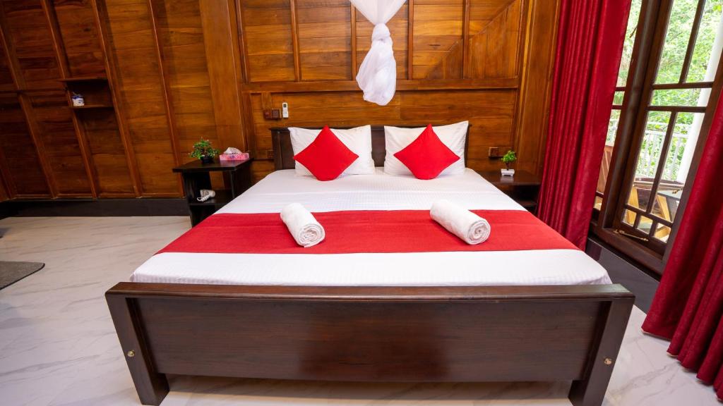 ein Schlafzimmer mit einem Bett mit roten und weißen Kissen in der Unterkunft Shady mango villa in Sigiriya