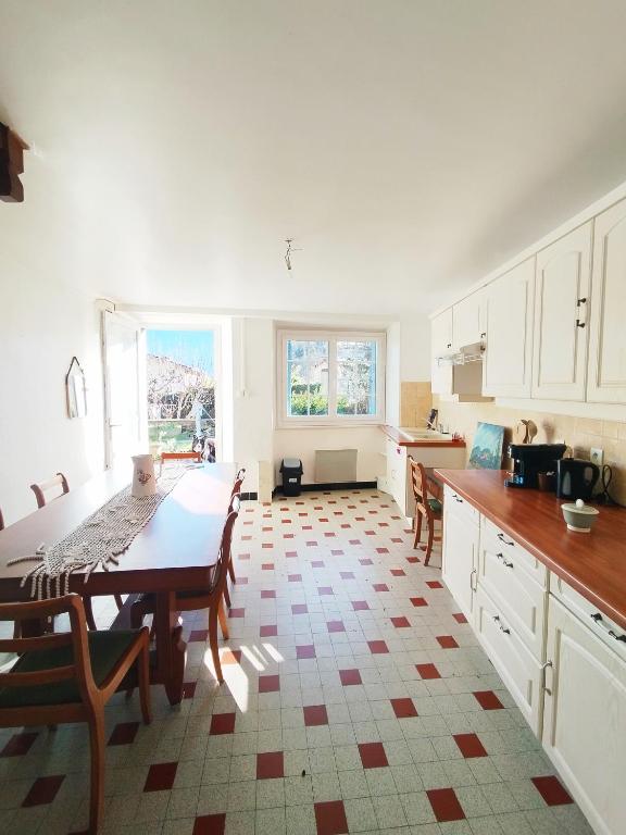 a kitchen with white cabinets and a table in it at Gite La Tanière in Siradan