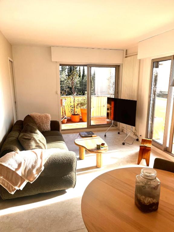 ein Wohnzimmer mit Sofa und Tisch in der Unterkunft Green cocoon in Mandelieu-la-Napoule