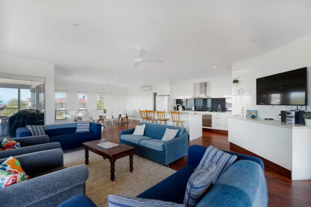 a living room with blue couches and a kitchen at The Summer Residence Middleton in Middleton