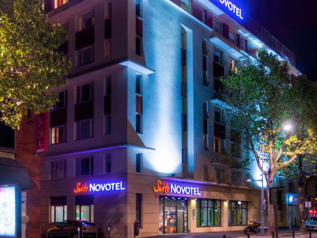 a building with neon signs on the side of it at Novotel Suites Clermont Ferrand Polydome in Clermont-Ferrand