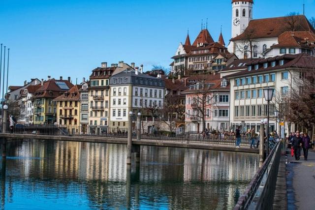 LaVida Wave Lakeside Haven am Thunersee & Alps في ليسيغن: مجموعة مباني بجانب تجمع المياه