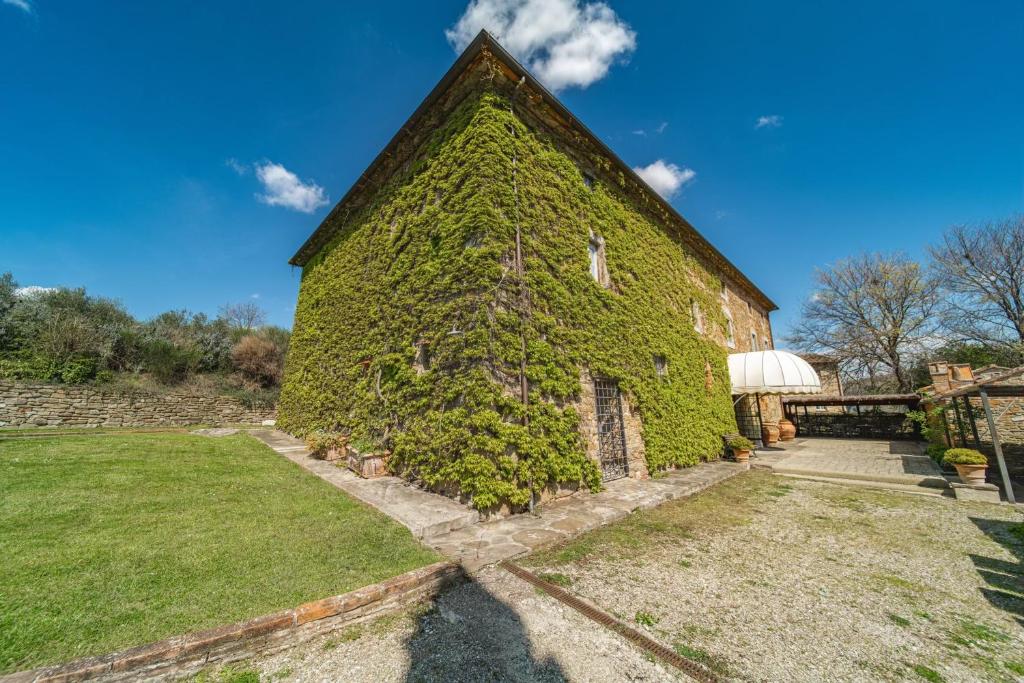 un vecchio edificio ricoperto di edera con un cortile di Santantimo Tuscany Inn ad Arezzo