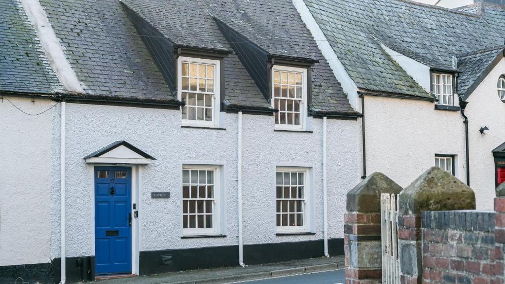 a white house with a blue door on a street at Rutherglen in Beaumaris