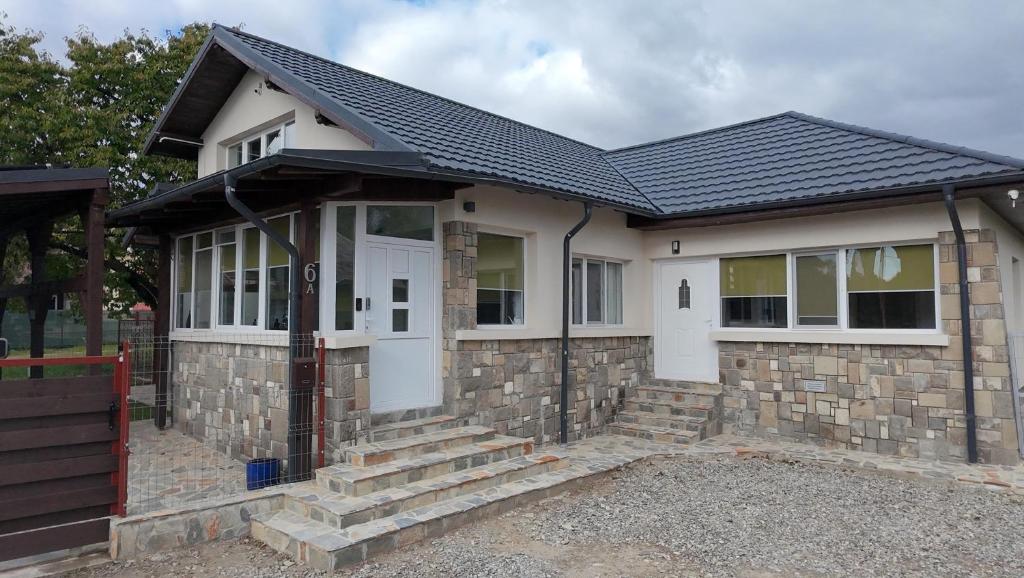 a small white house with a black roof at Vila Trifoi Apartamente in Breaza de Jos