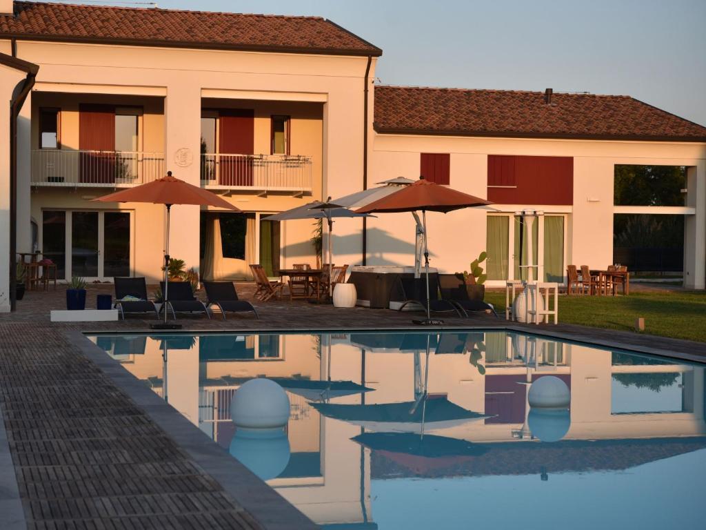 a swimming pool in front of a house with umbrellas at Domus Natura, un'oasi verde tra Padova e Venezia in Vigonza