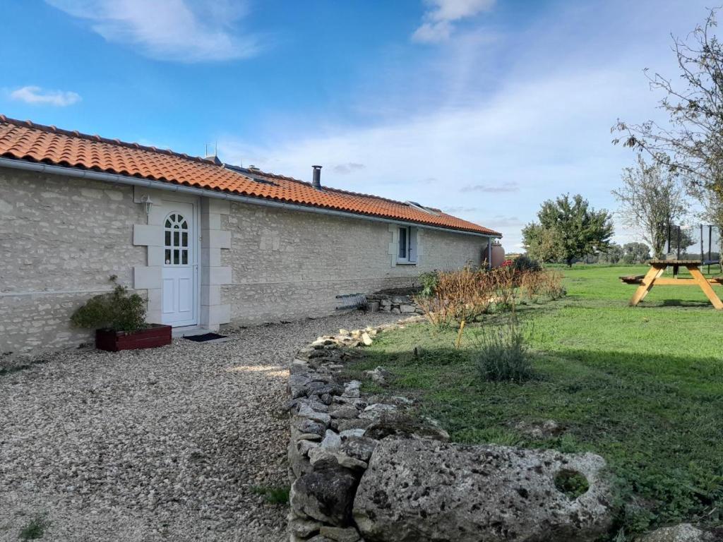 a house with a stone wall in front of a yard at La bergerie in Coussay