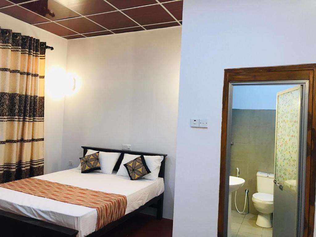 a bedroom with a bed and a bathroom with a toilet at Shereen Sigiri Homertay in Dambulla