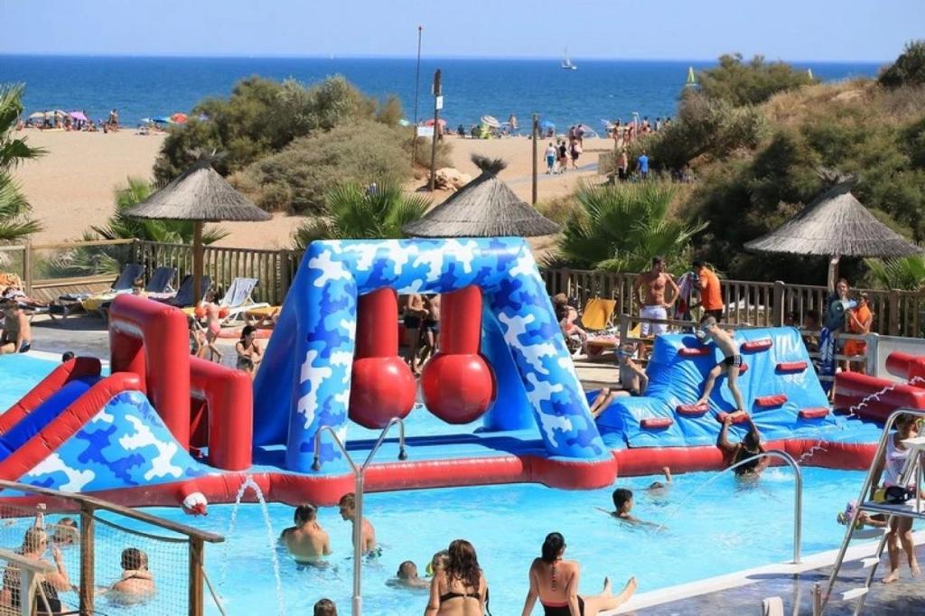 a group of people in a swimming pool at a beach at ZEcamping 4 étoiles chiens acceptés piscine chauffée et toboggans in Portiragnes