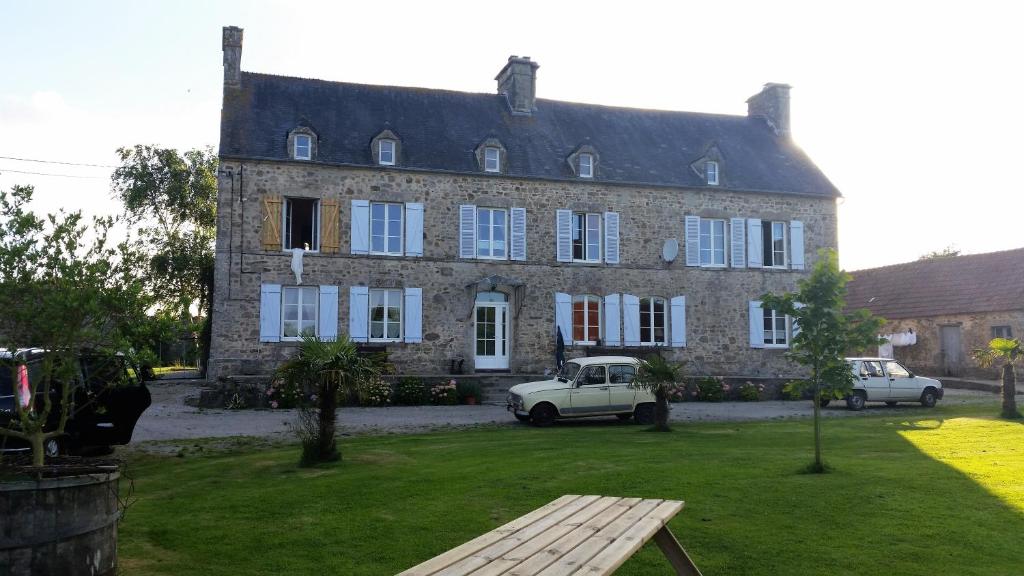 Chambre d’hôtes La Ferté في Saint-Floxel: منزل قديم مع سيارة متوقفة أمامه