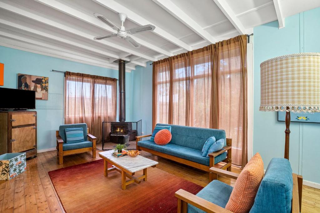 ein Wohnzimmer mit einem blauen Sofa und Stühlen in der Unterkunft Retro Beach Babe 100 metres to the beach in Tootgarook