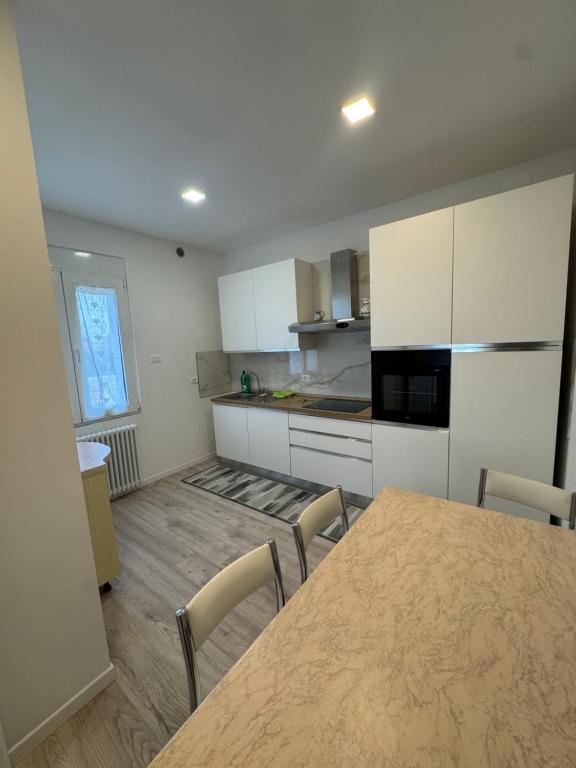 House 31 Plus في مونفالكوني: مطبخ مع خزائن بيضاء وطاولة وكراسي