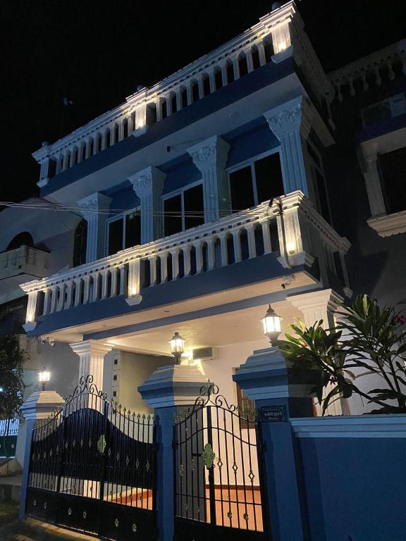 a white house with a blue fence in front of it at De Pondy beachside Villa in Pondicherry