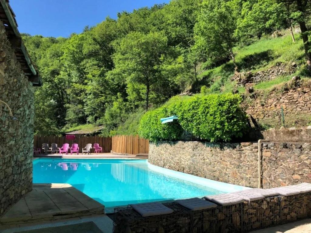 a swimming pool with a stone wall next to a mountain at ZEcamping 3 étoiles avec piscine bar et restaurant en bord de ruisseau in Belguiral
