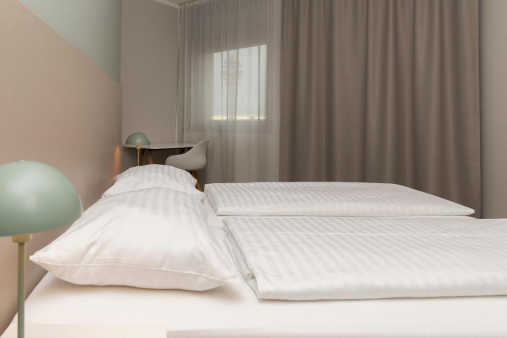 zwei Betten in einem Schlafzimmer mit weißen Wänden in der Unterkunft HANS-Y Apartments inklusive Outdoorpool & Bar in Wien