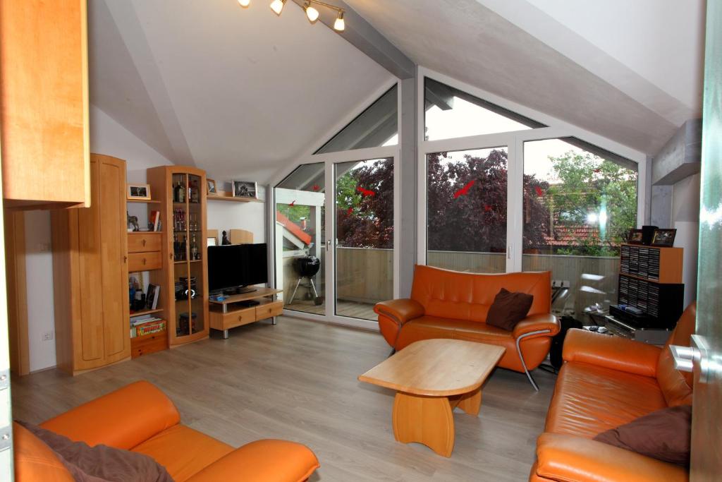 ein Wohnzimmer mit orangefarbenen Möbeln und großen Fenstern in der Unterkunft Traumhafte 3-Zi-Ferienwohnung im Alpenvorland in Kolbermoor