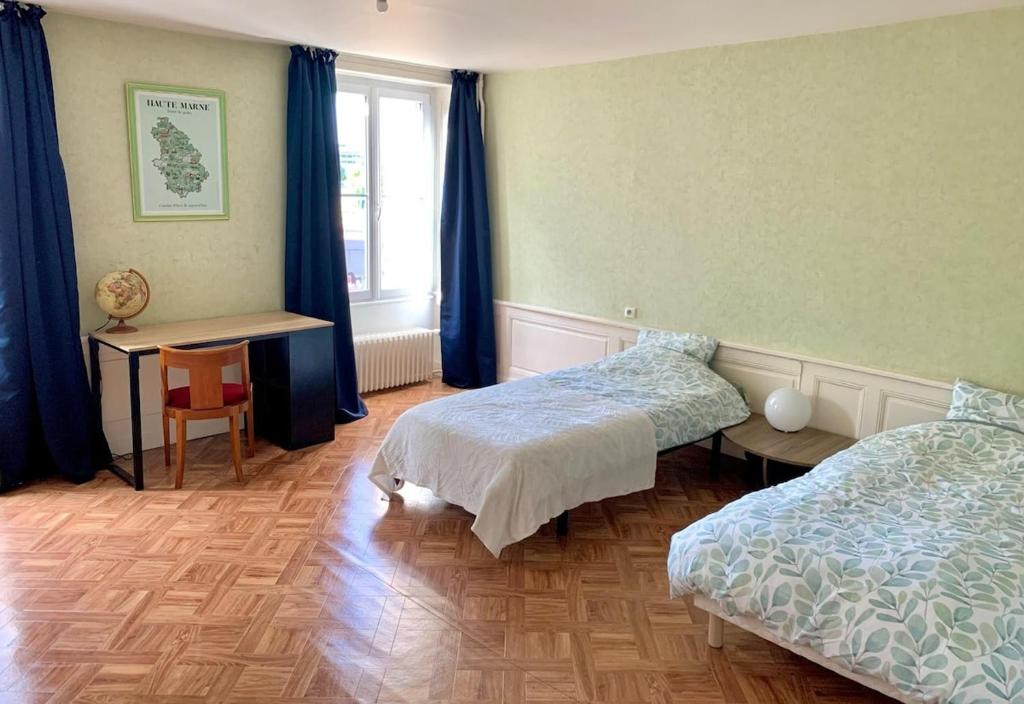 Un dormitorio con dos camas y una mesa y una ventana. en Proche gare et centre-ville, en Chaumont