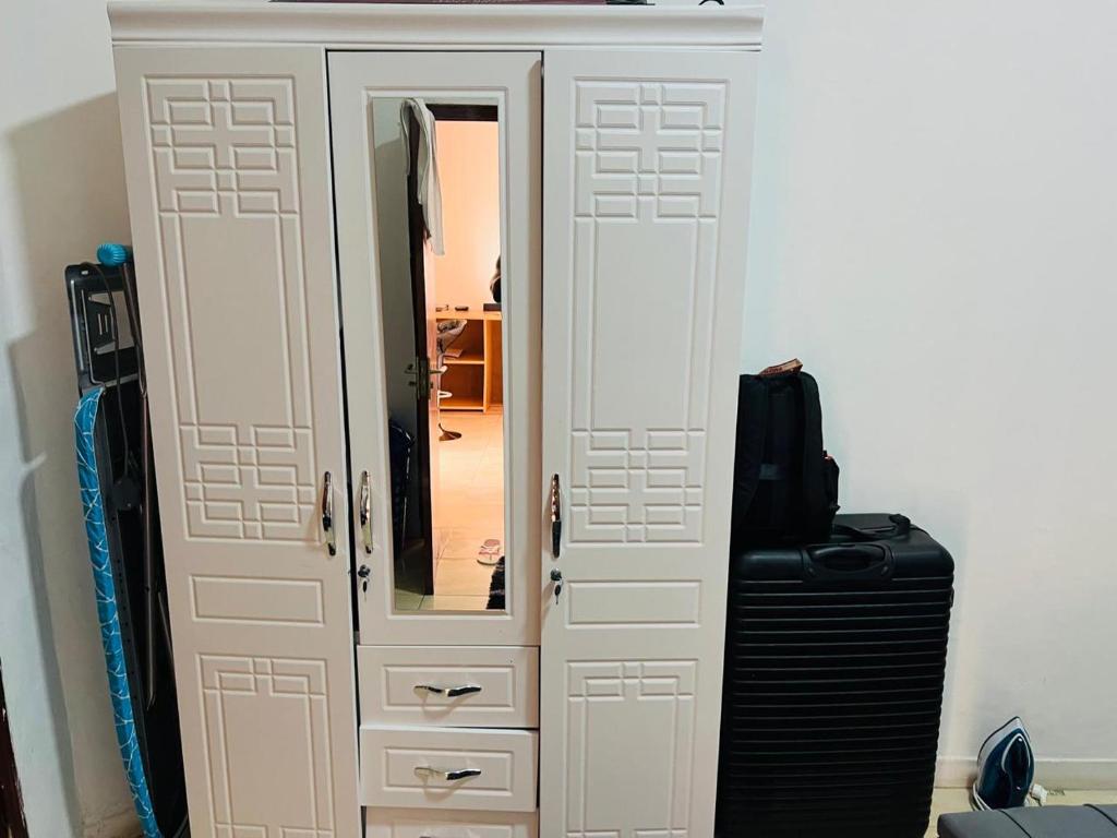 Apartamento Rua Rainha Ginga في لواندا: خزانة بيضاء مع مرآة وحقيبة سفر