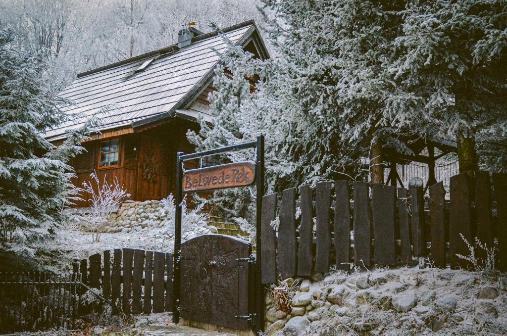 ein Haus mit Zaun und einem Schild im Schnee in der Unterkunft Domek Góralski Belwederek ski-in ski-out z prywatną sauną in Karpacz