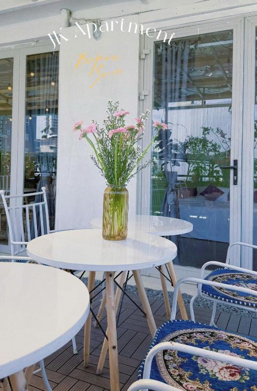 Cozy 2BR Retreat with Outdoor Living & Garden في دا نانغ: طاولتان وكرسيان مع زهور في مزهرية