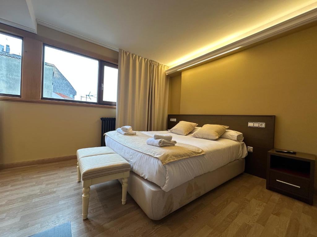 a bedroom with a bed and a chair and windows at Hotel Santa Catalina by Bossh Hotels! in A Coruña