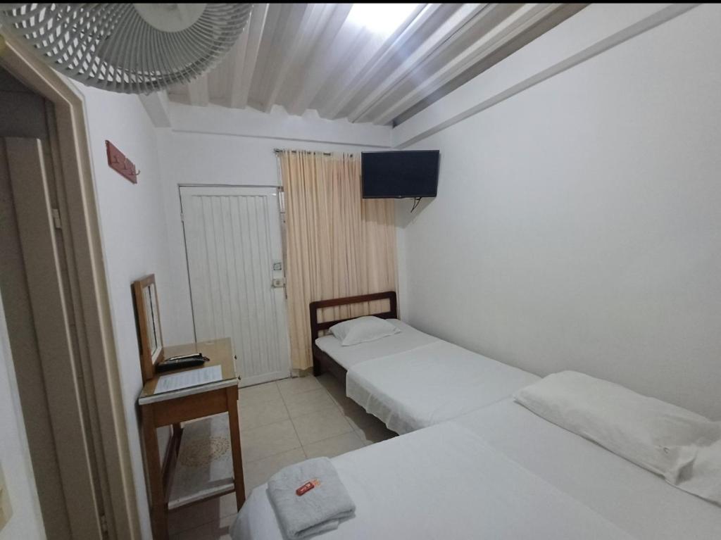 a small room with two beds and a television at Hotel Comercial Neiva EZ in Neiva