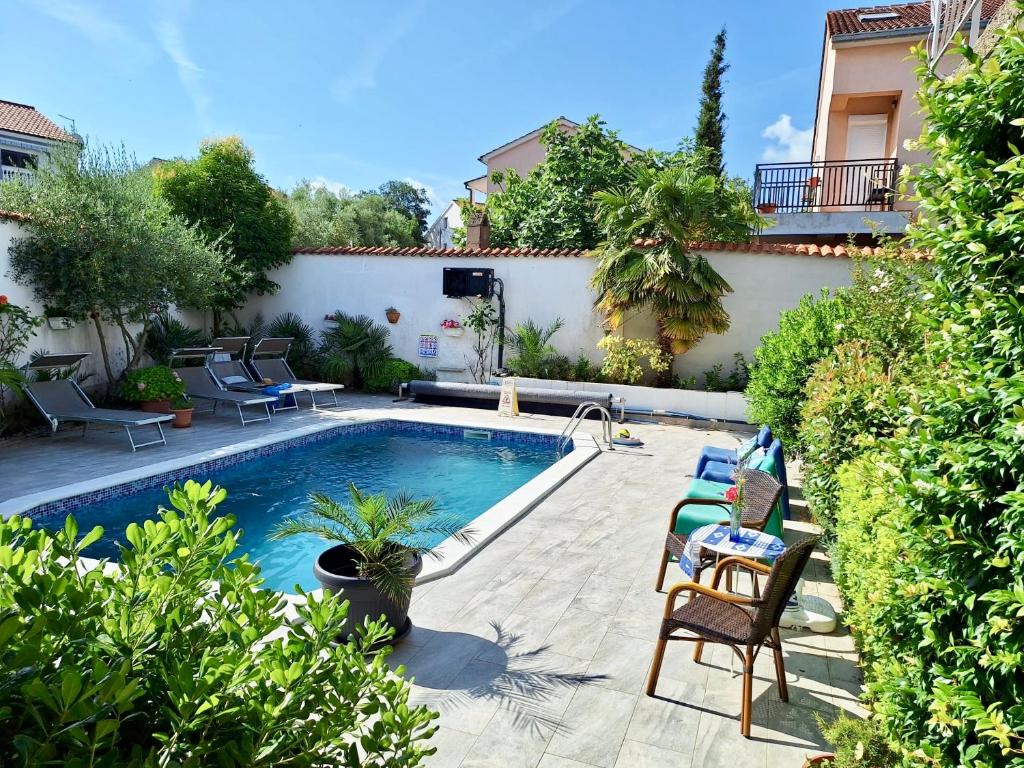 a swimming pool in a yard with chairs and plants at Apartment with private pool and arbor in Malinska