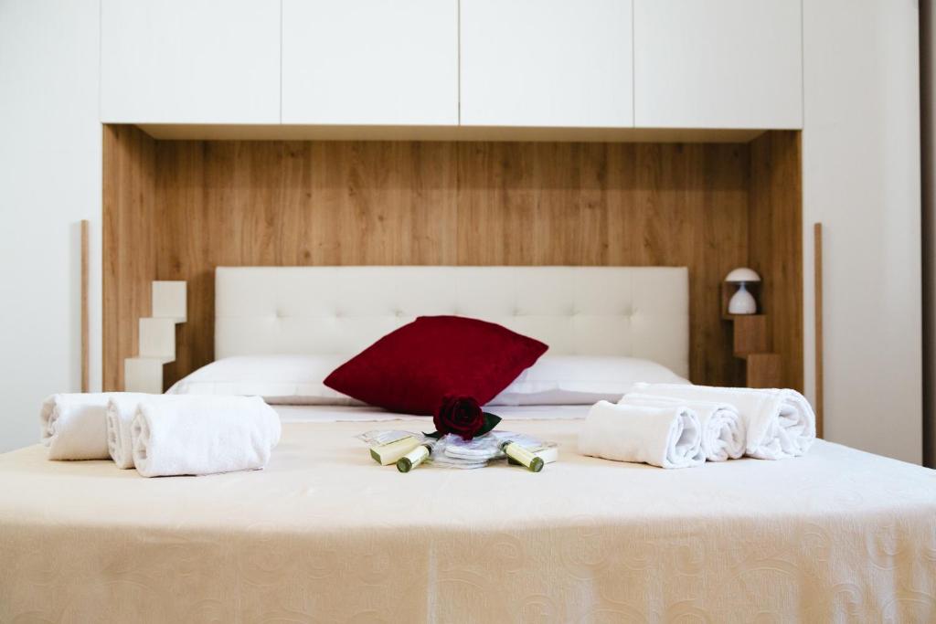 Giù in Calabria B&B - Terrazze Italiane Catanzaro Lido في كاتانزارو ليدو: سرير أبيض كبير مع مناشف بيضاء ووسادة حمراء