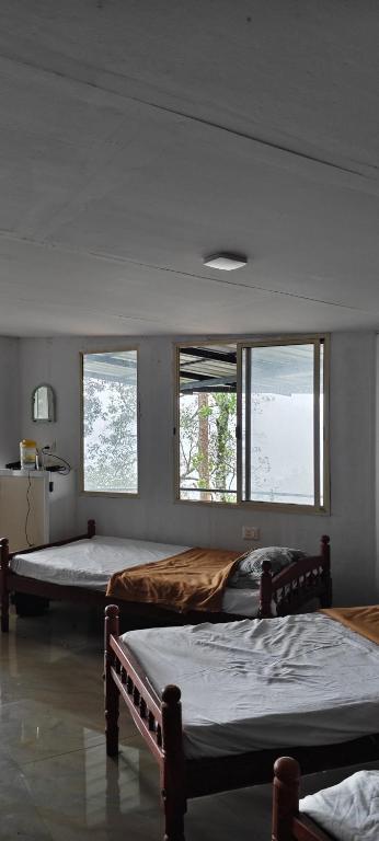 two beds in a room with three windows at Valley Homestay in Devikolam
