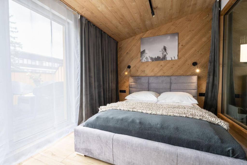 a bedroom with a large bed with a wooden wall at Apartamenty Krupówki 20 in Zakopane