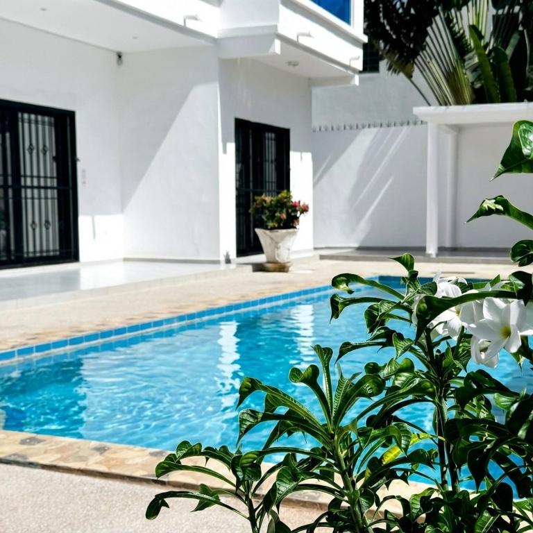 a swimming pool in a house with a plant at Villa Maurice in Mbour