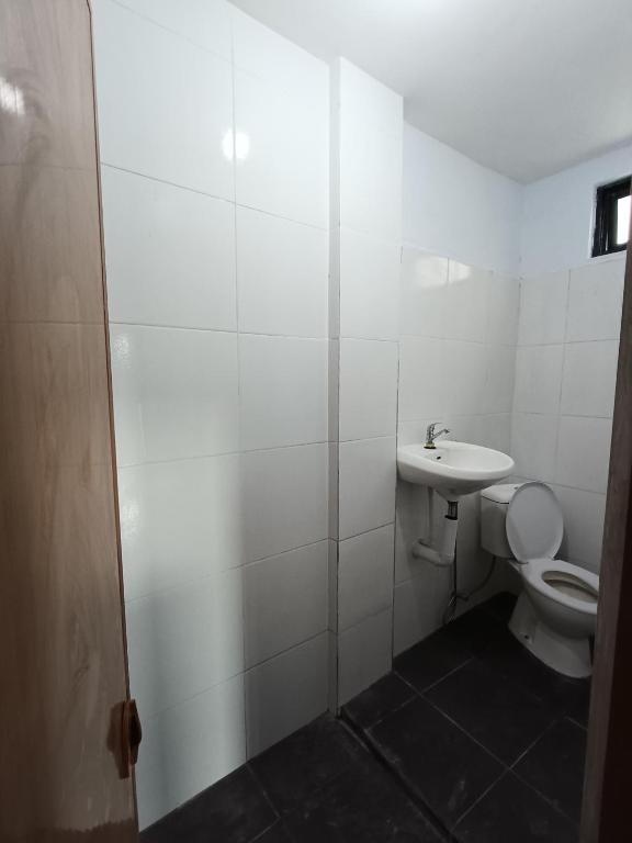 a white bathroom with a toilet and a sink at WiNHOUSE 2 in Legian